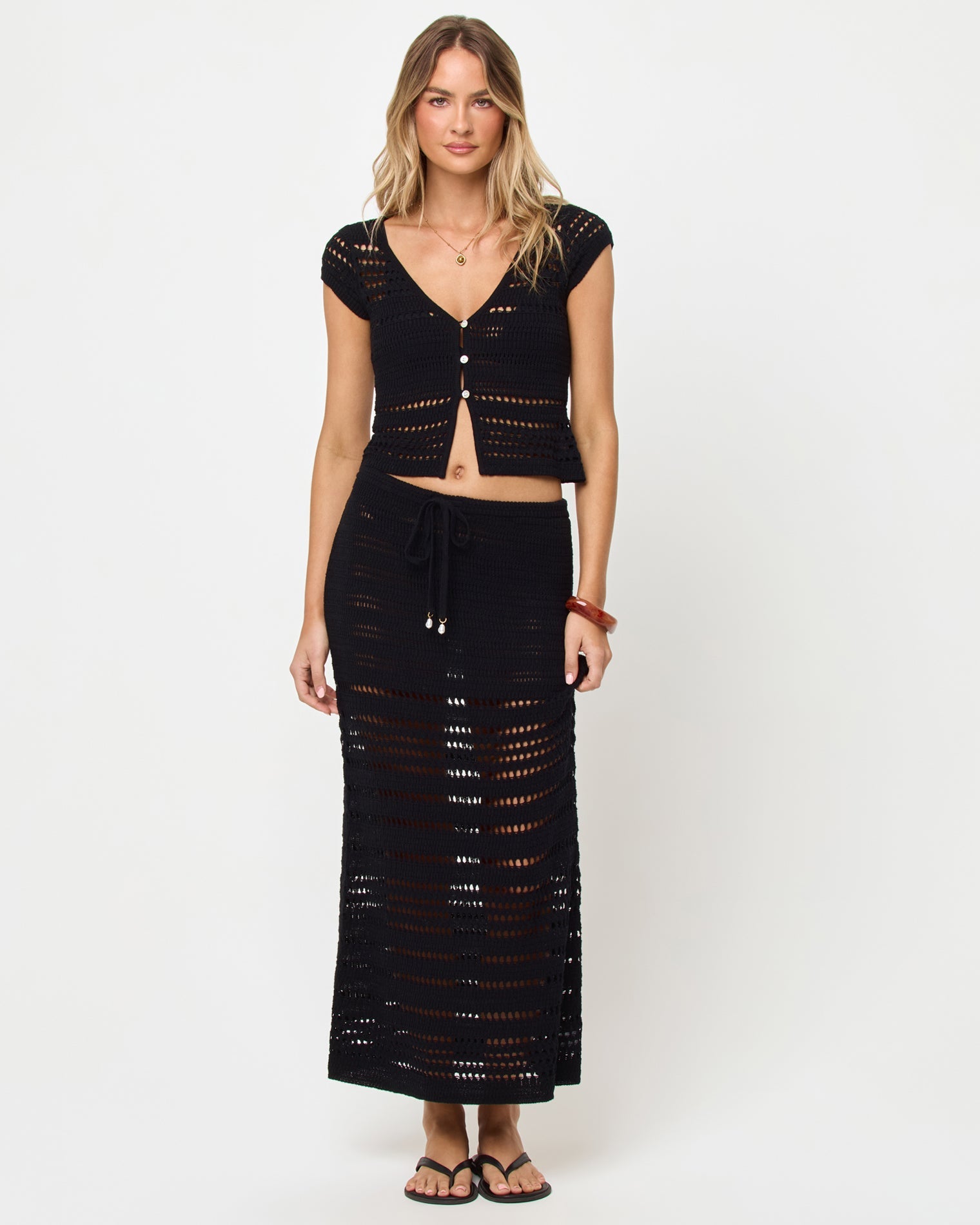 Haut court en maille crochet noire, col en V, manches courtes et boutonnage devant