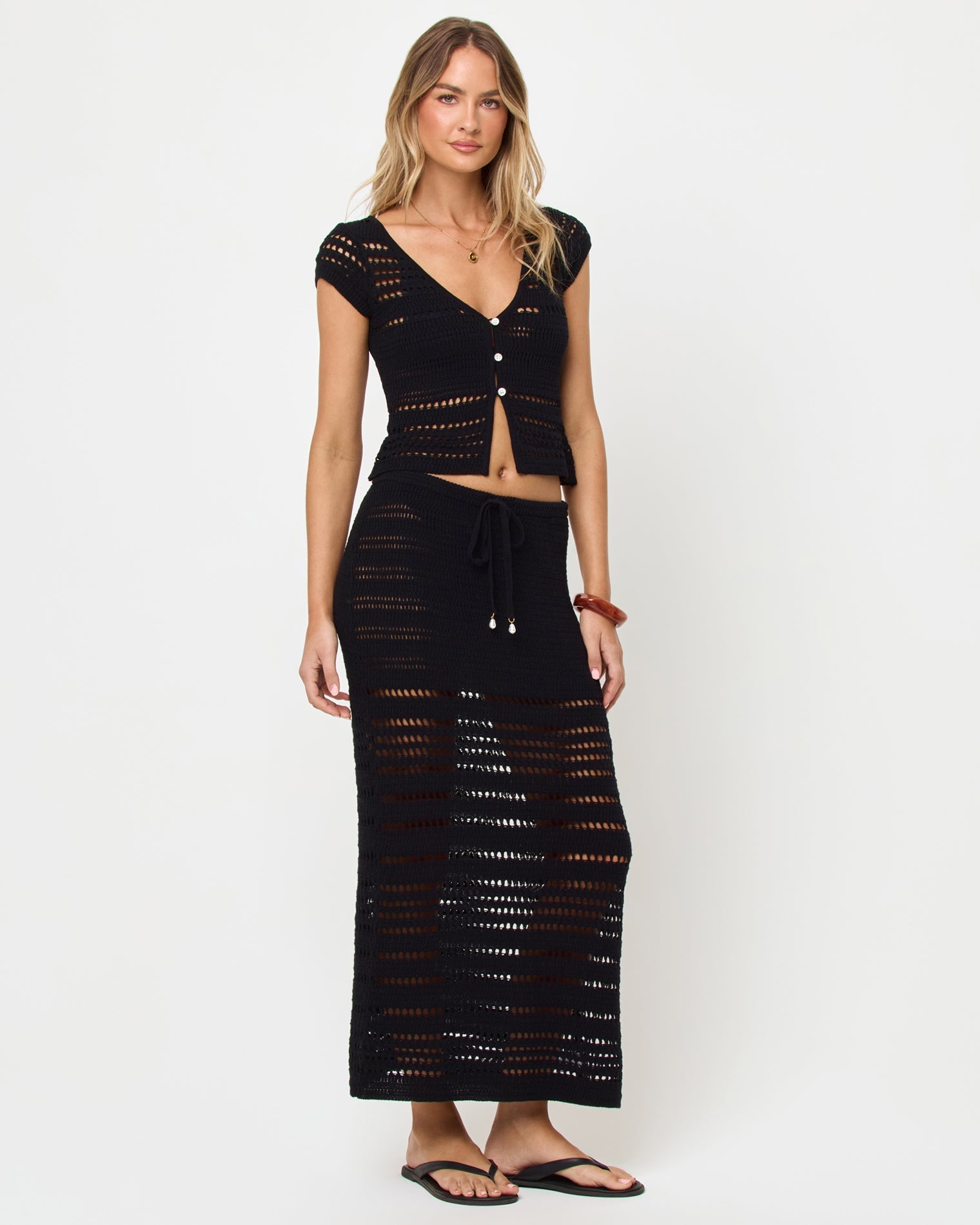 Haut court en maille crochet noire, col en V, manches courtes et boutonnage devant